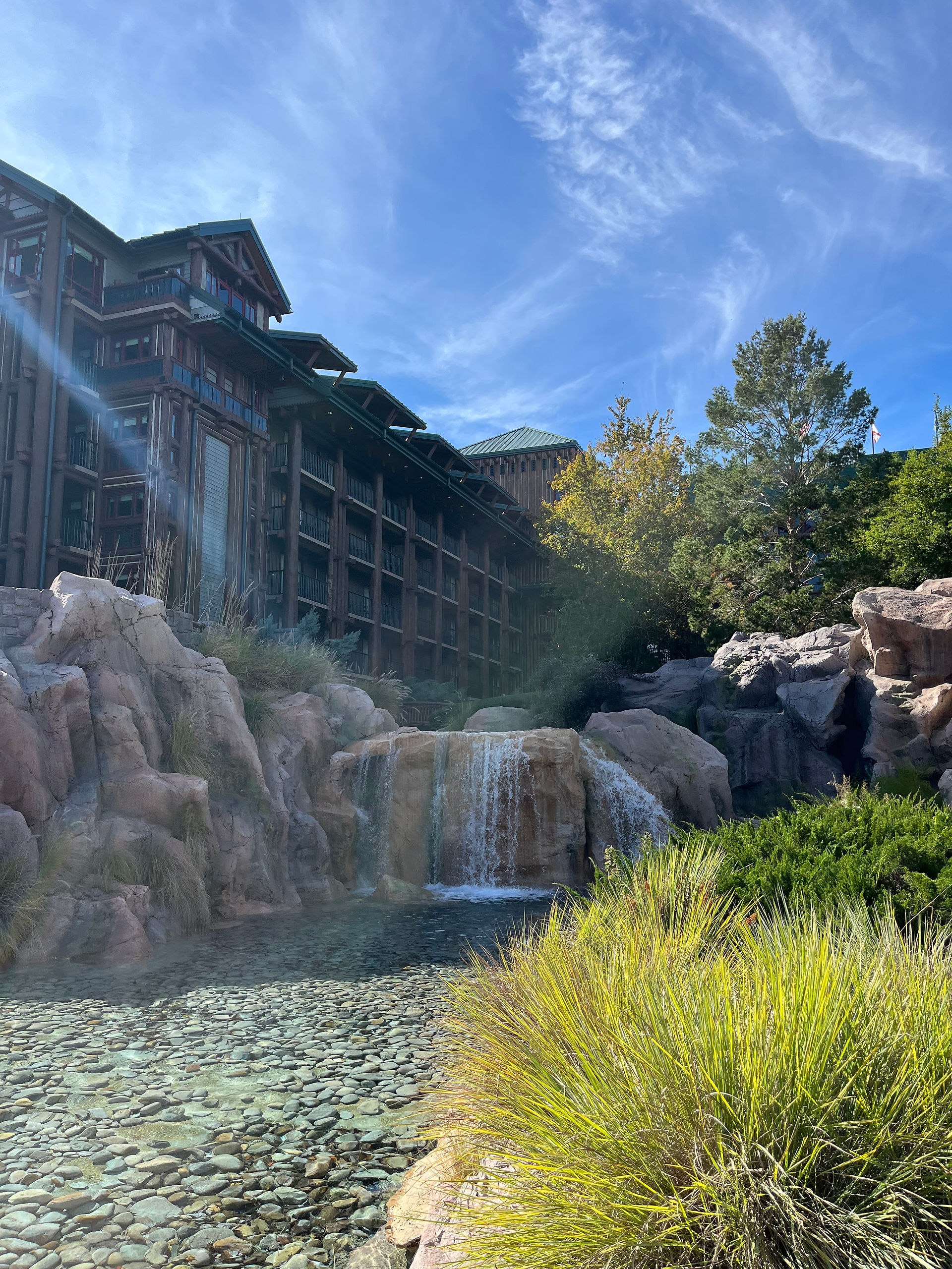 Wood cabin appearing resort with waterfall and greenery
