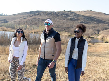 Three cheerful hikers pose side by side in a winter field