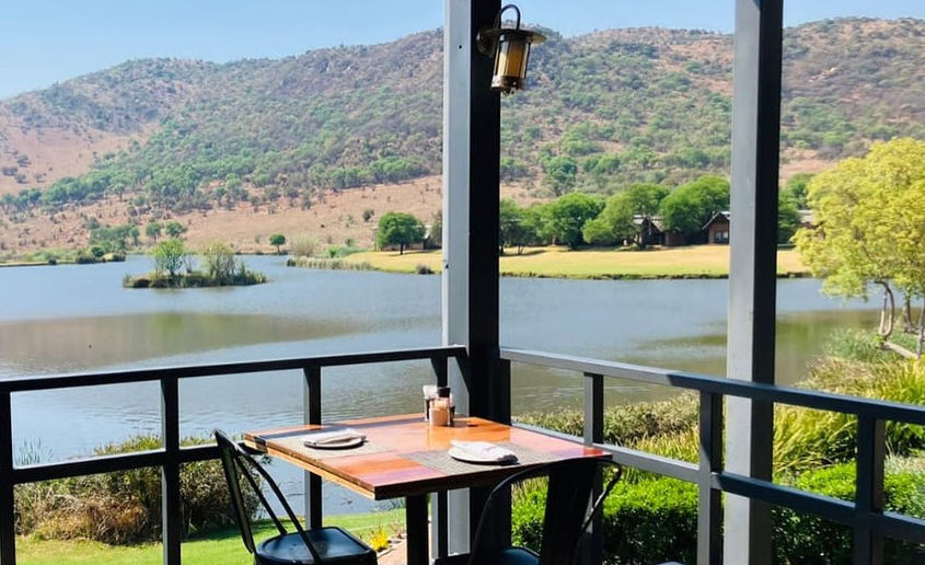 View from a lodge veranda overlooking a lake and mountain landscape at Kloofzicht.