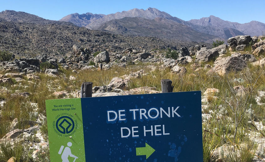 A hiking sign pointing towards "De Tronk, De Hel".