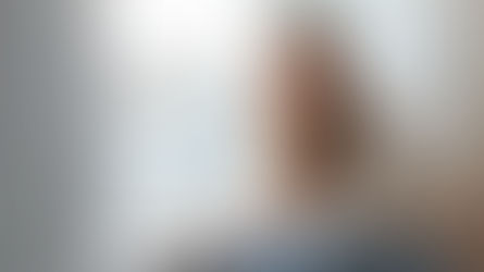 Nachdenkliche junge Frau vor einem Fenster.