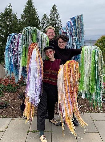 the 3 performers/artists of In Touch / In Motion pose for a photo with their arms raised wearing flowy textile sleeves