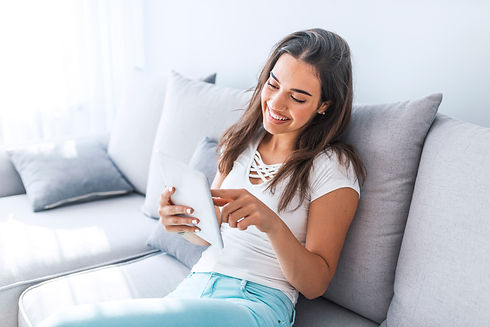cheerful-woman-lying-cosy-couch-bright-living-room-using-tablet-pc.jpg