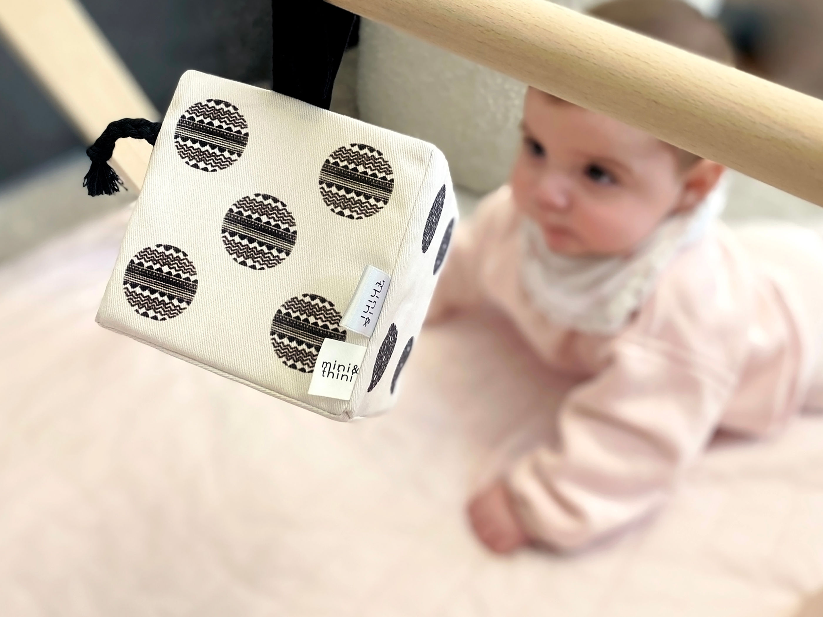 First Dice hanging of a wooden baby gym with baby on the background during tummy time