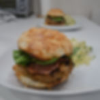 two plates, each with a burger on a cheese bun and a side of green cabbage coleslaw