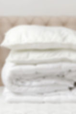 Stack of neatly folded white household linens against plain background representing professional washing, folding, and cleaning for towels, sheets, and home fabrics at CleanMeNow in Draper Utah