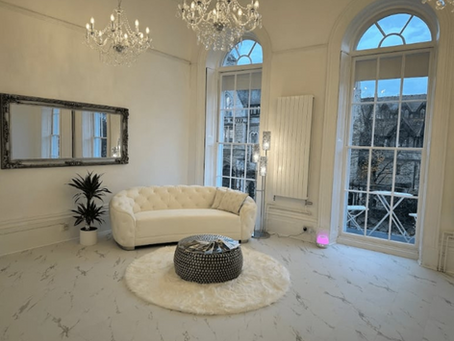 White leather sofa in front of large windows with a round rung and coffee table in front