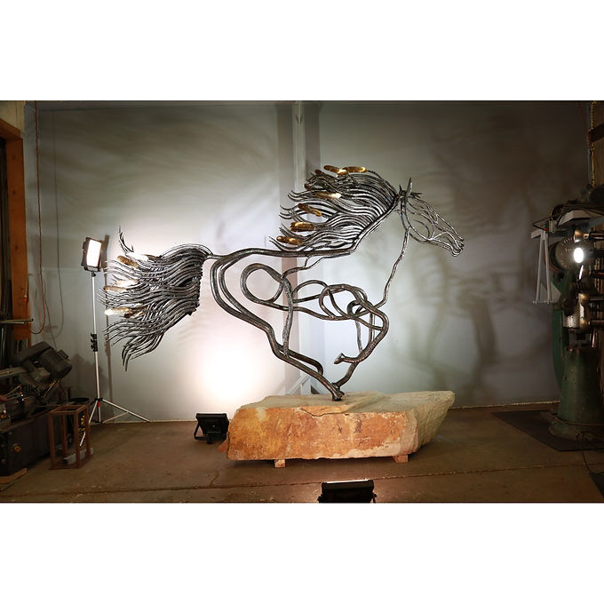 A galloping horse drawn in looping lines of steel, the mane and tail flaring with brass-coloured accents, mounted on a slab of stone.