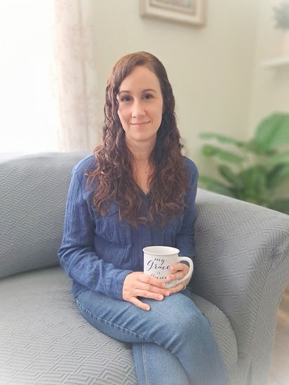 Profile of sleep consultant, Andrea Estacion sitting on couch holding coffee mug.