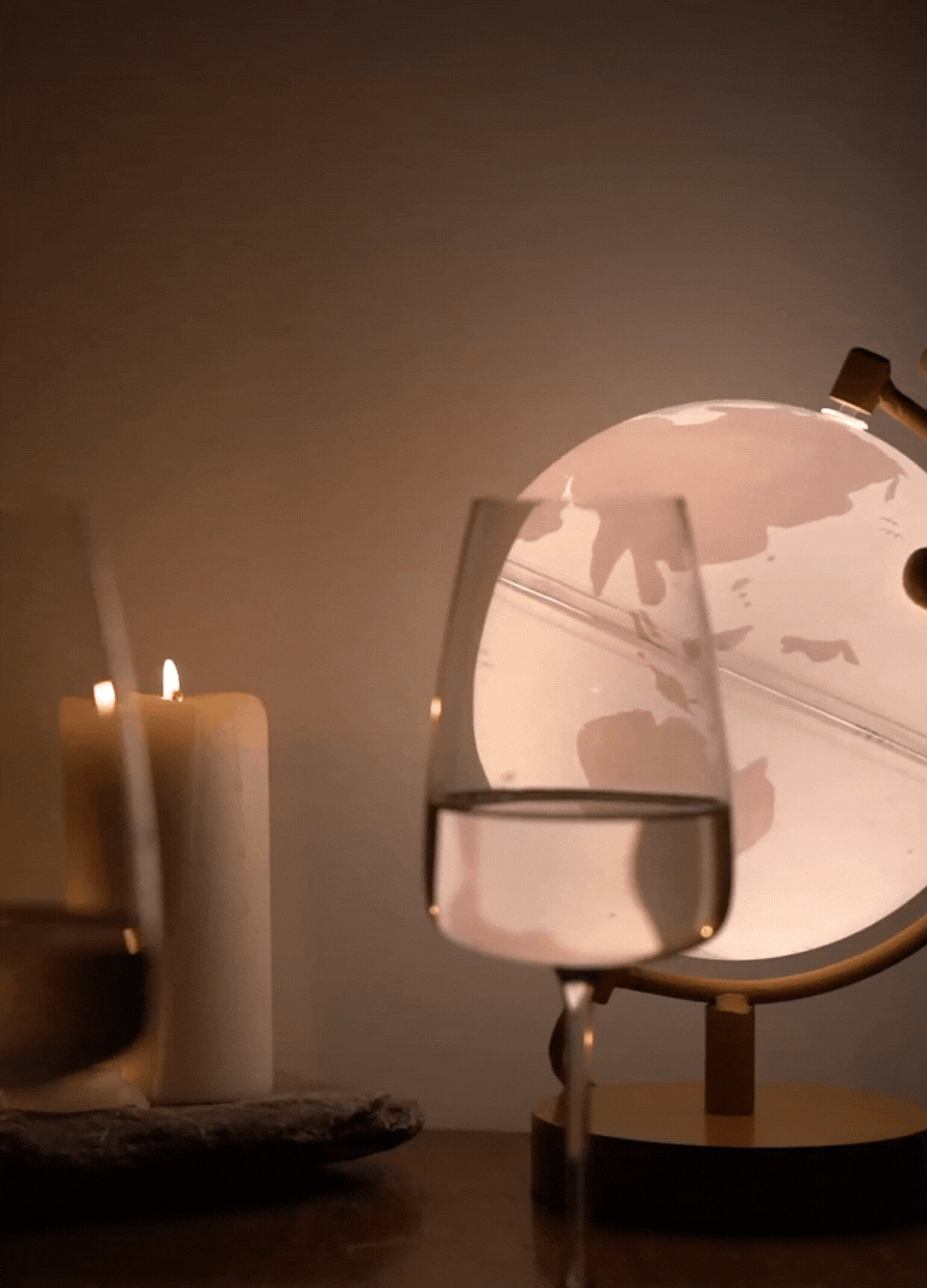 light up world globe spinning slowly behind a glass of white wine