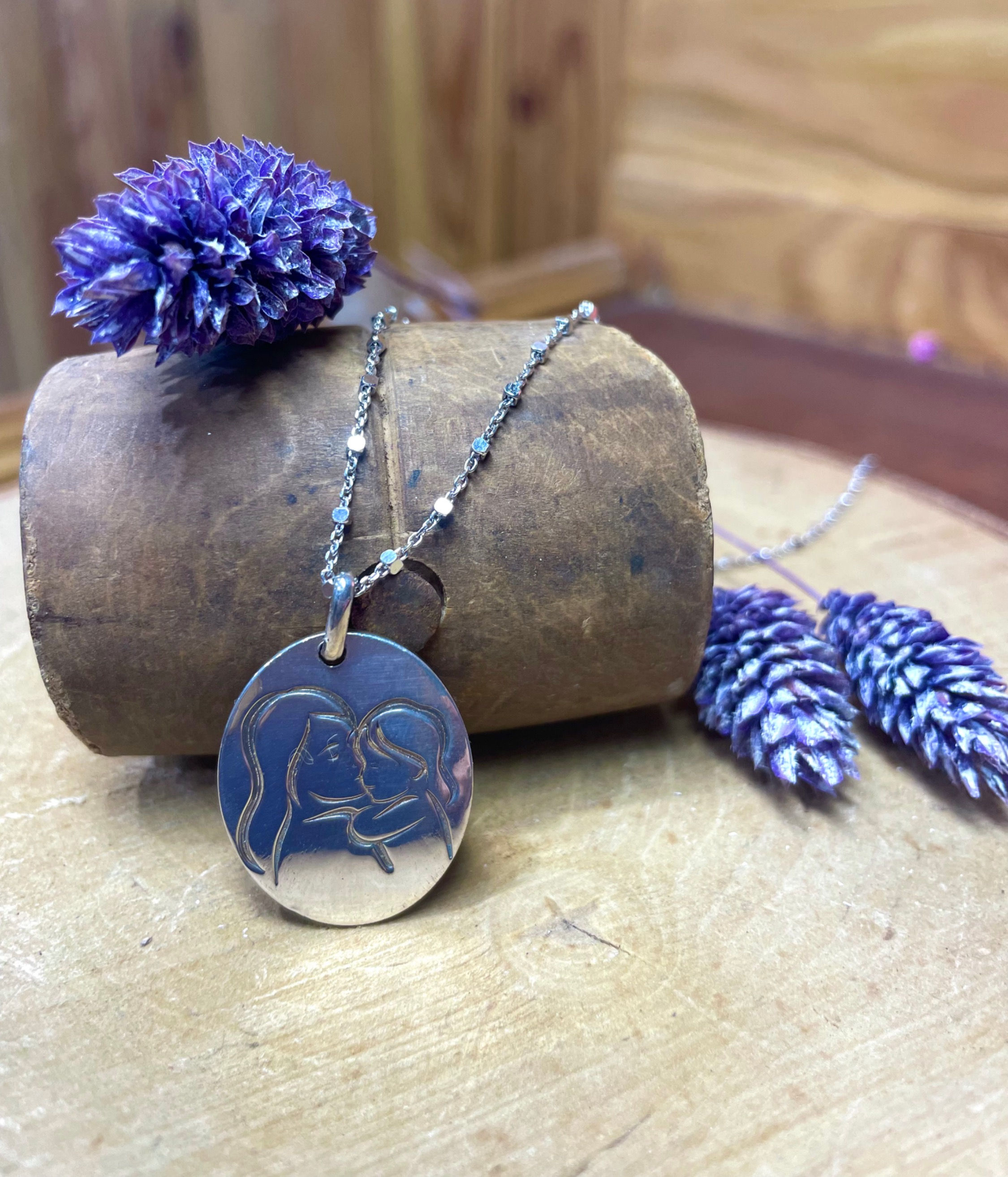 C'est un pendentif mère et fille en Argent 925 où est gravé la tête d'une femme enlaçant sa petite fille. 