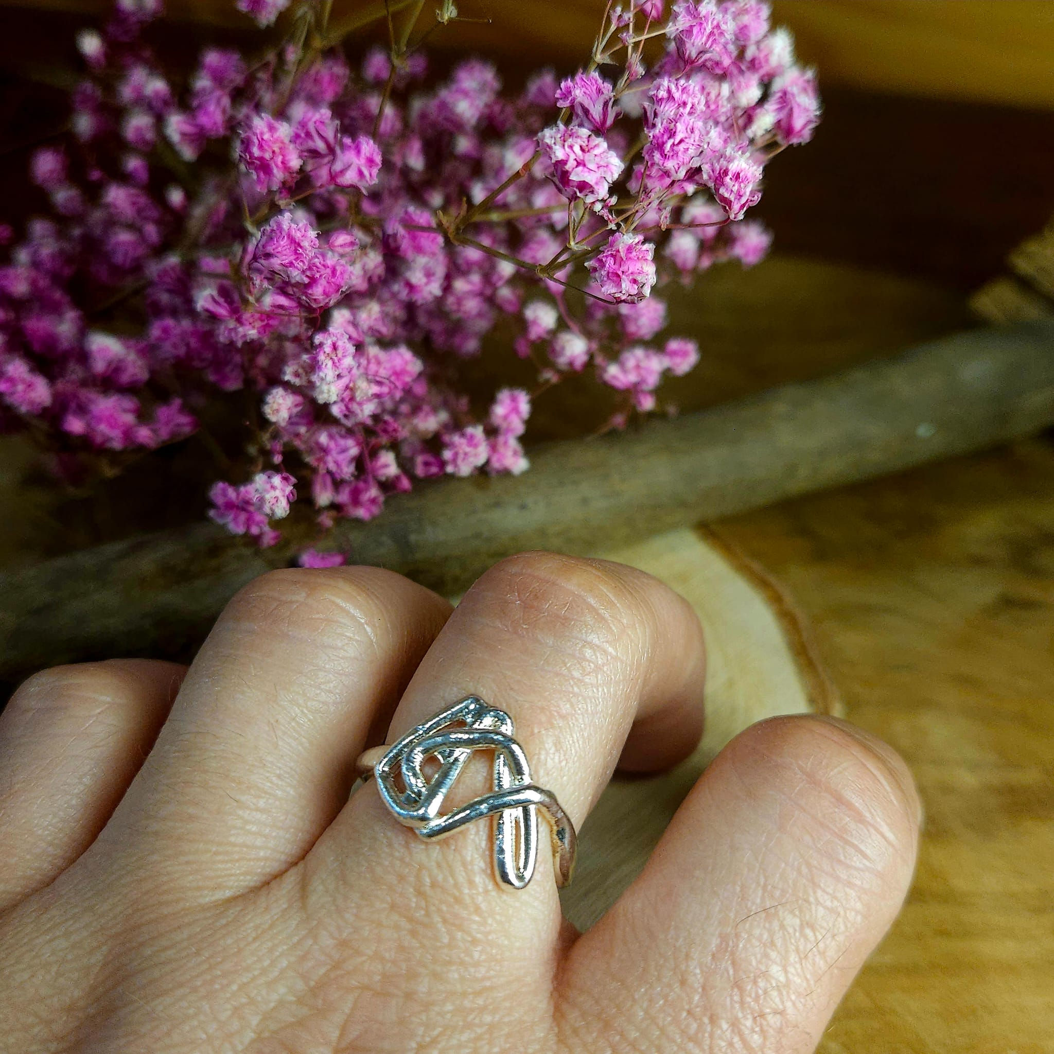 Il s'agit d'une bague tout en argent, qui a une forme originale, elle suit plusieurs courbes différentes qui se rejoignent, un peu comme de l'art abstrait. 