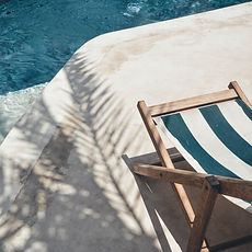 brown wooden lounger near body of water_