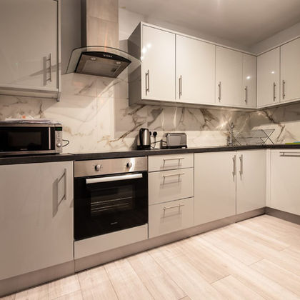 Modern kitchen with gray cabinets, oven, and marble backsplash