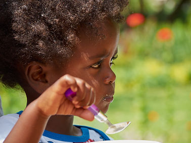 Adorable black African baby eating with food full face.jpg