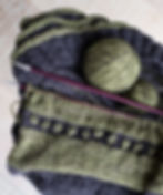 Green and dark grey wool sweater in the process of being knitted