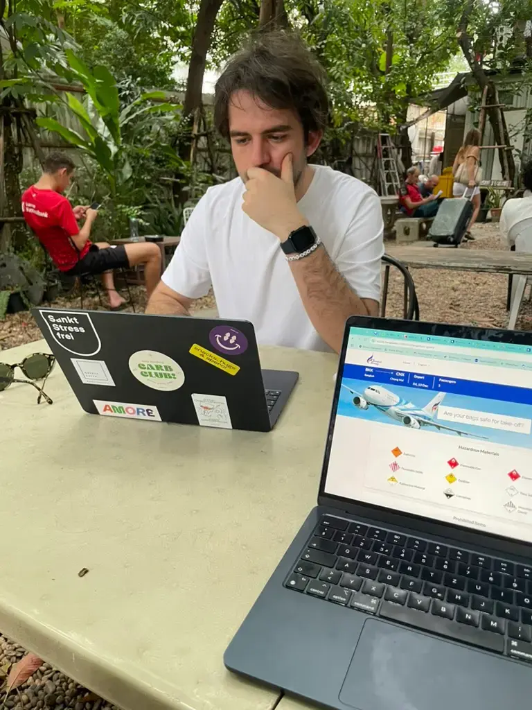 Working remotely on a laptop using a Saily eSIM connection at The Yard hostel in Bangkok, Thailand