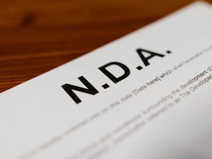Close-up of an NDA document on a wooden table, with bold N.D.A. text and blurred contract lines in the background.