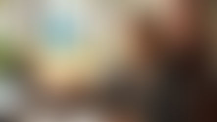 Notary woman in an office with palm trees view, holding a glowing house shield icon. She looks confident. Laptop and papers on desk.