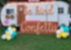 a boho-inspired mobile trailer with a large Be Kind Confetti sign and balloons in the yard