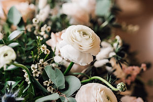 part of a bridal bouquet showing a white ranunculus and wax flower.