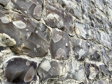 Gros plan du mur extérieur du Château de Louÿe, montrant le matériau de pierre unique utilisé