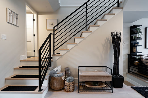 Stunning home entrance featuring a staircase renovation with crafted wood steps and sleek black railings, enhancing the look of this beautiful Vancouver home renovation.