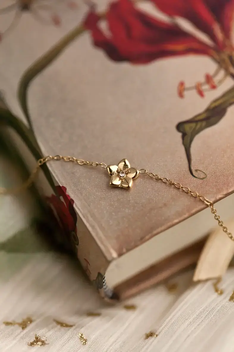 bracelet en acier inoxydable doré avec une toute petite fleur aux pétales pointus et un petit strass au centre