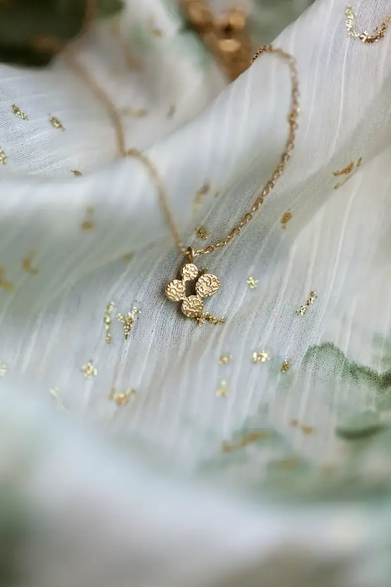 collier en acier inoxydable doré avec un pendentif composé de quatre médailles rondes texturées formant une forme de trèfle