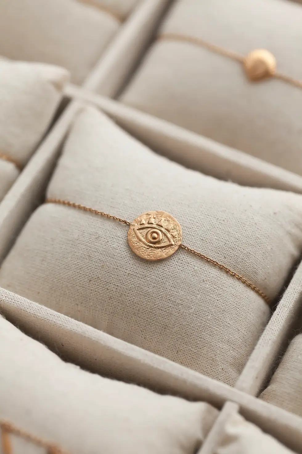 bracelet en plaqué or pour femme avec une médaille texturée et un oeil en relief