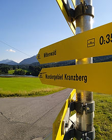 Close-up of a yellow road sign pointing to nearby Bavarian towns, including Mittenwald.