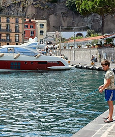 Child fishing by the water at the port of Sorrento.