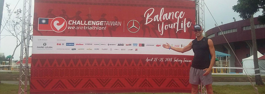 Triathlete standing in front of Challenge Family Taiwan banner before race week