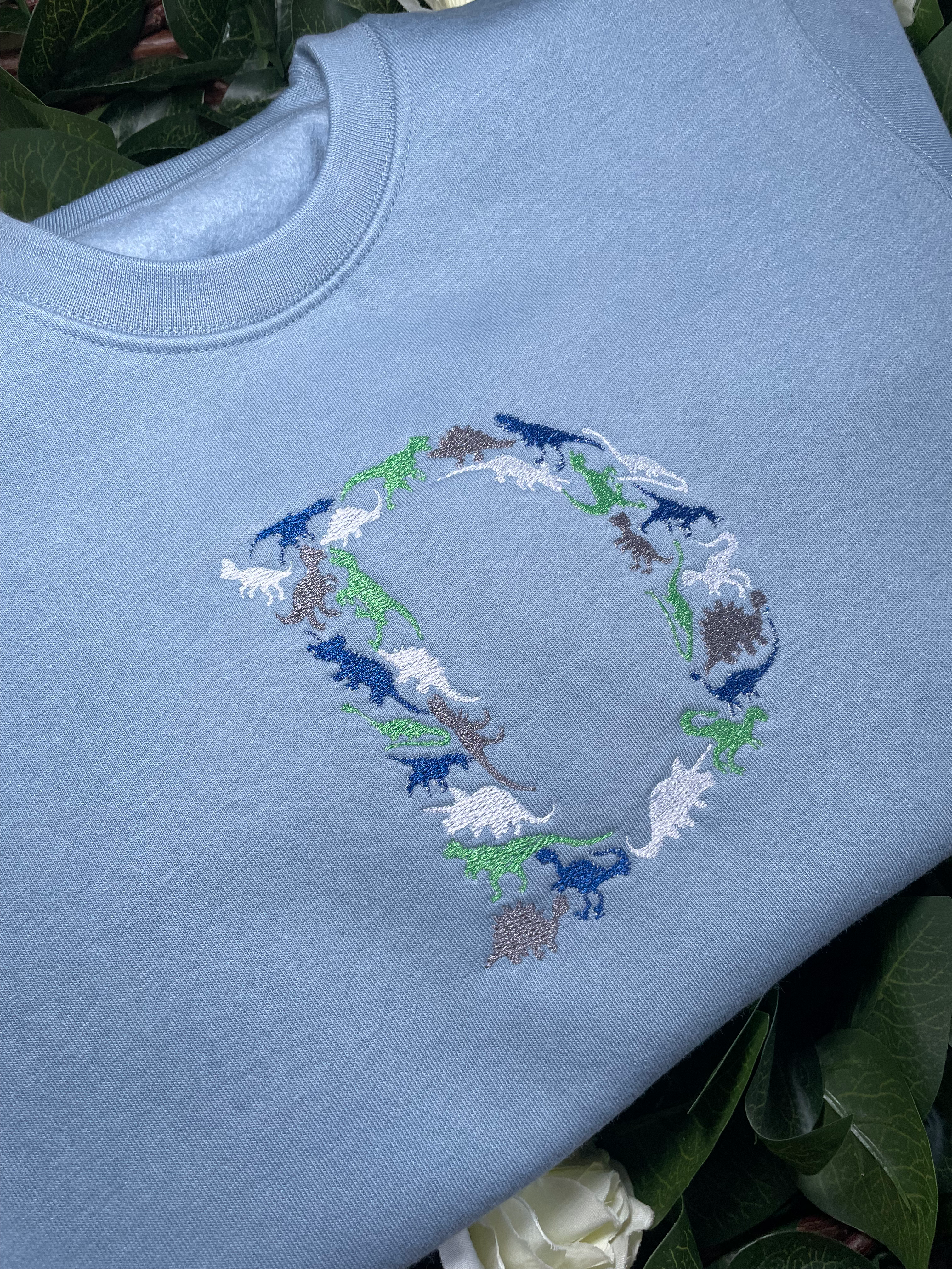 Kids personalised sweatshirts, embroidered with a dinosaur initial.