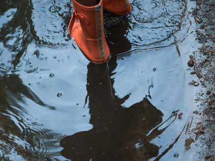 Røde jentestøvler i vannpytt. Foto: Crystal Peartree.