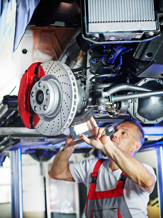 An image of a car suspended in the air while a mechanic works on its wheel