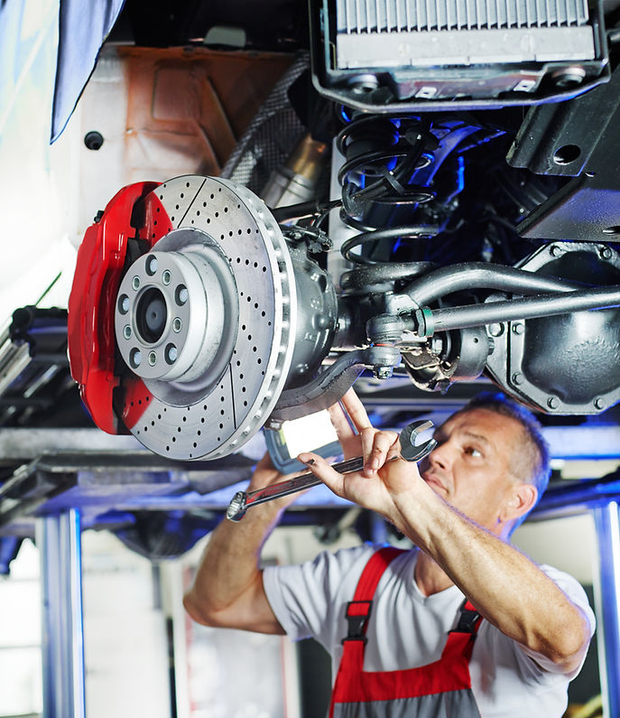 An image of a car suspended in the air while a mechanic works on its wheel