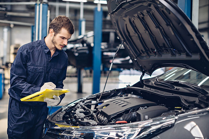 A mechanic is reviewing and taking notes about a car's engine