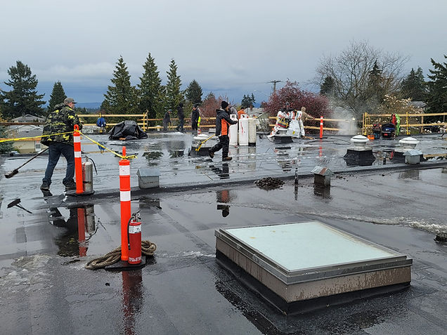 Wide-angled view showing several workmen cleaning a rooftop on a rainy day.