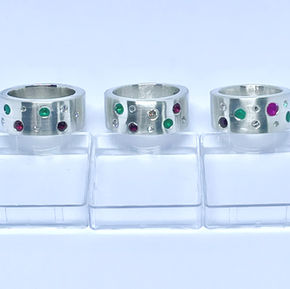Silver rings each flush set  with round diamonds, rubies and emeralds 