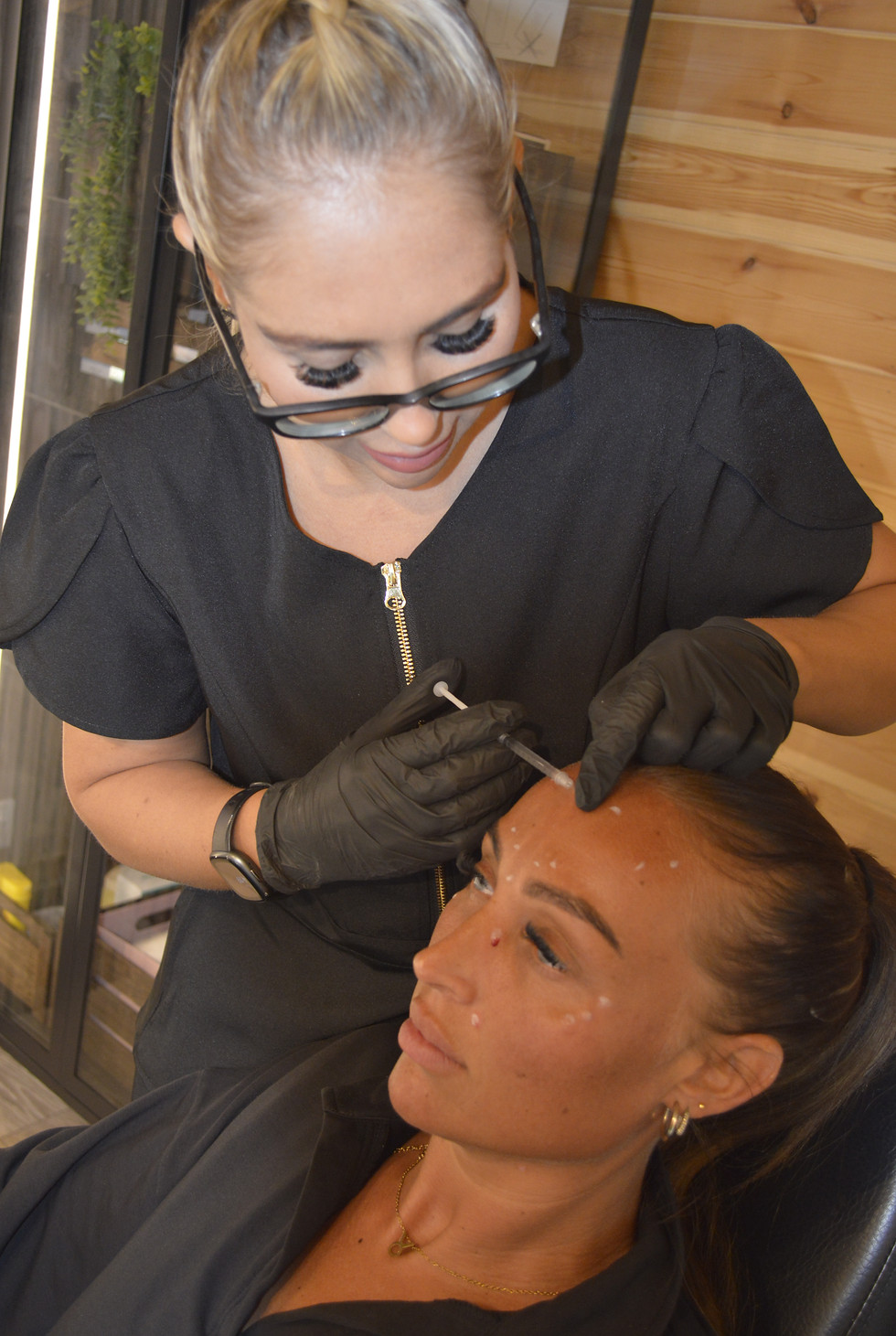 Woman receiving eyebrow treatment from technician