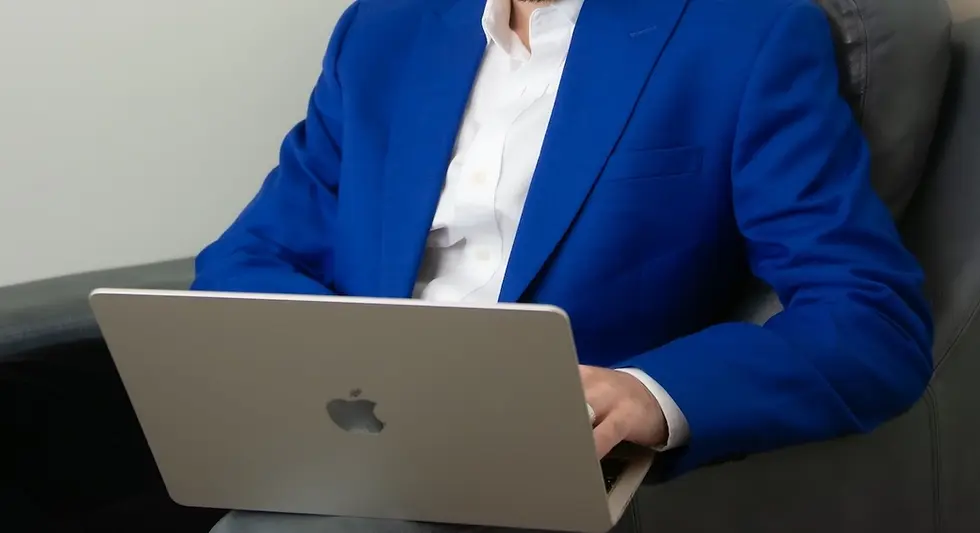 Business English instructor in a blue blazer using an Apple laptop in a modern office