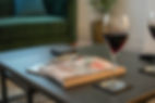 Background image of coffee table with glass of wine. Link to access guest reviews on Airbnb & Booking.com