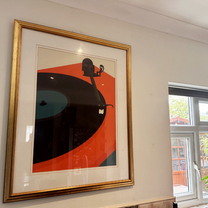Stylus turntable print in a gold frame on a wall