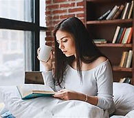 Natural light flows the window as her hands and eyes scans for spiritual light through a rubble of spiritual literature.
