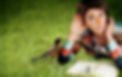 Meredith lying on the grass listening to a bird with a notebook in front of them