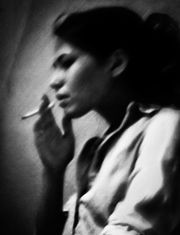 Jeune femme fumant une cigarette, visage flou, regard vers le bas