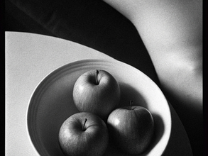 Nature morte en noir et blanc avec trois pommes dans une assiette et un fragment de corps féminin