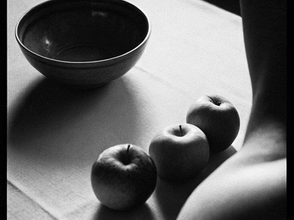 Nature morte en noir et blanc avec trois pommes, un bol sombre et un fragment de corps féminin