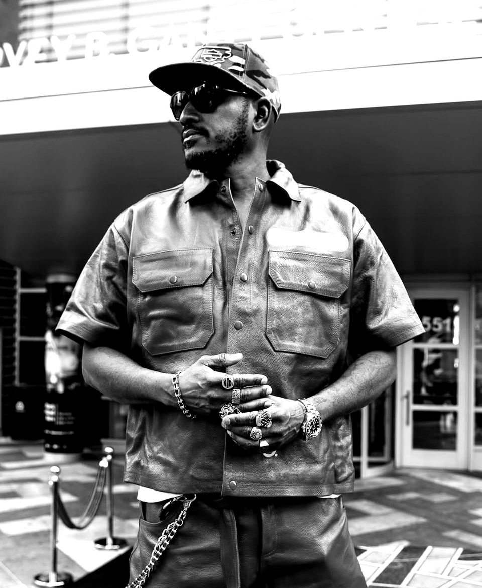 Grammy-winning rapper, Sean Paul, wearing sunglasses and military-style shirt, in front of building.